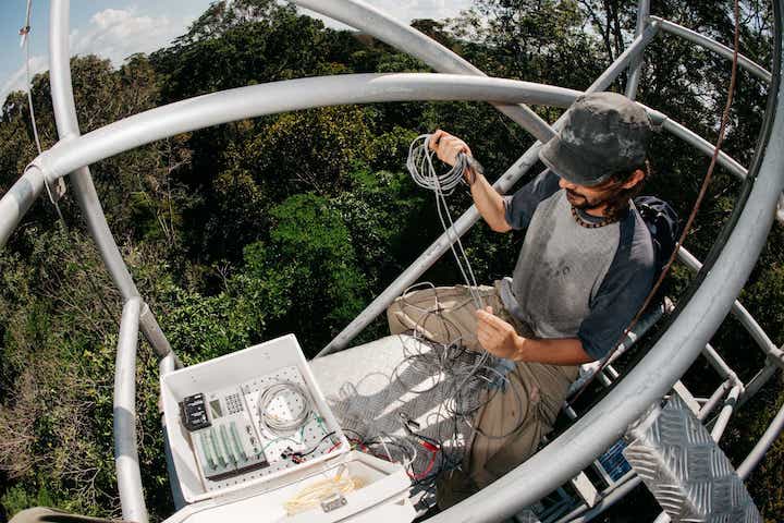 A male PhD student works on equipment high above the Amazon rainforest. Photo credit: Jake Bryant

